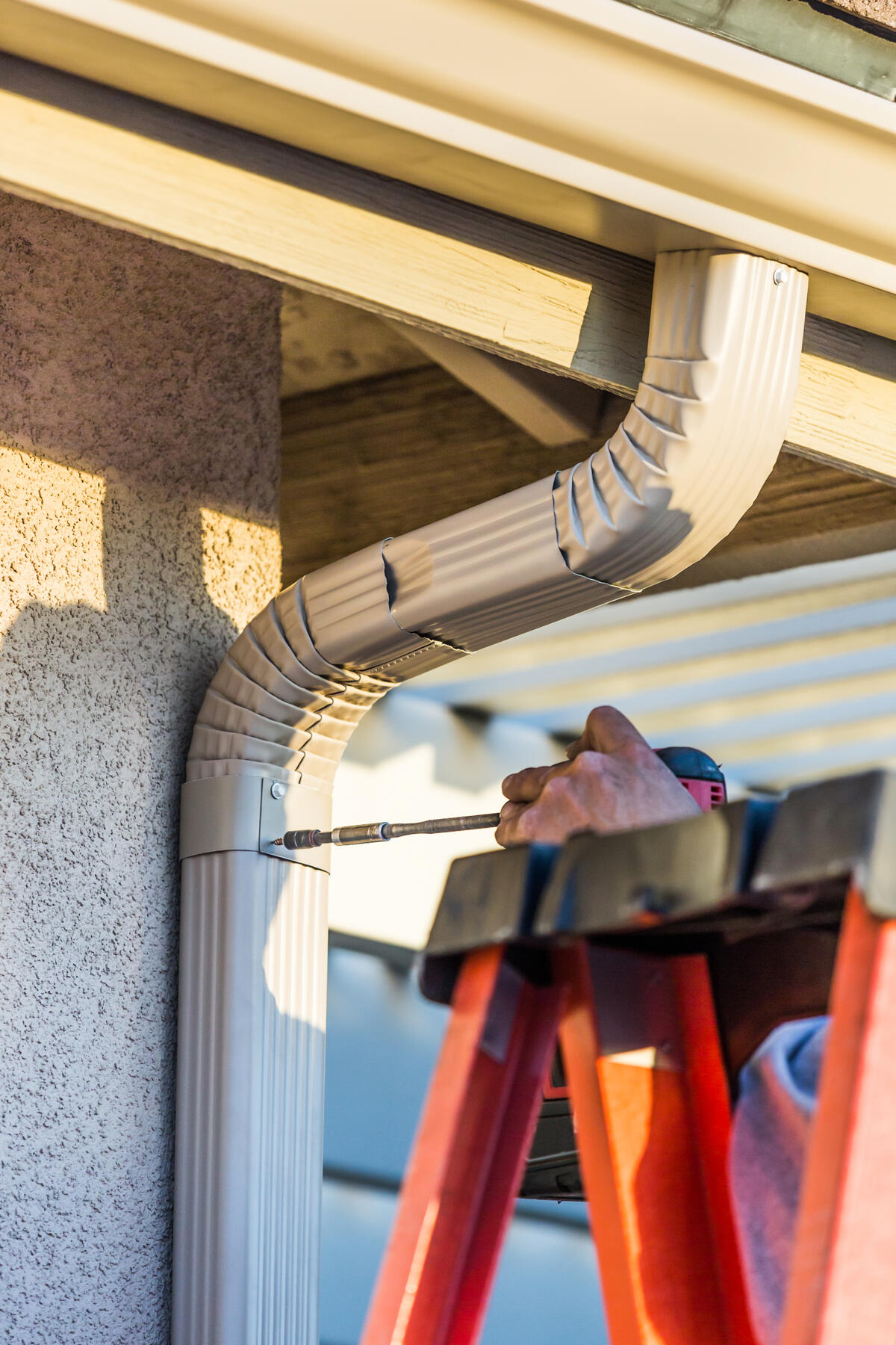 Professional installing seamless gutters on a residential home in Albuquerque. Final.