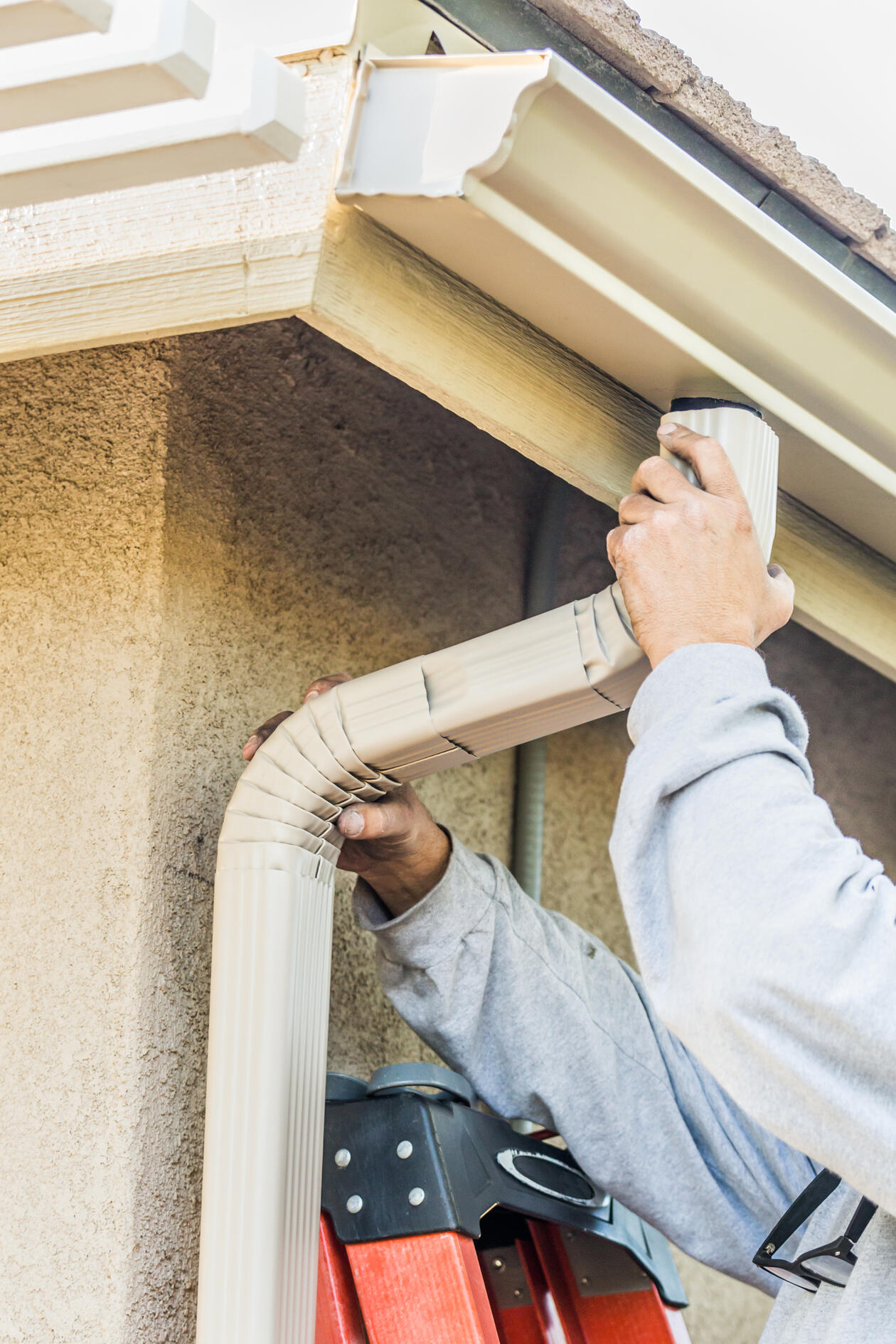 Professional installing seamless gutters on a residential home in Albuquerque. Downspout B