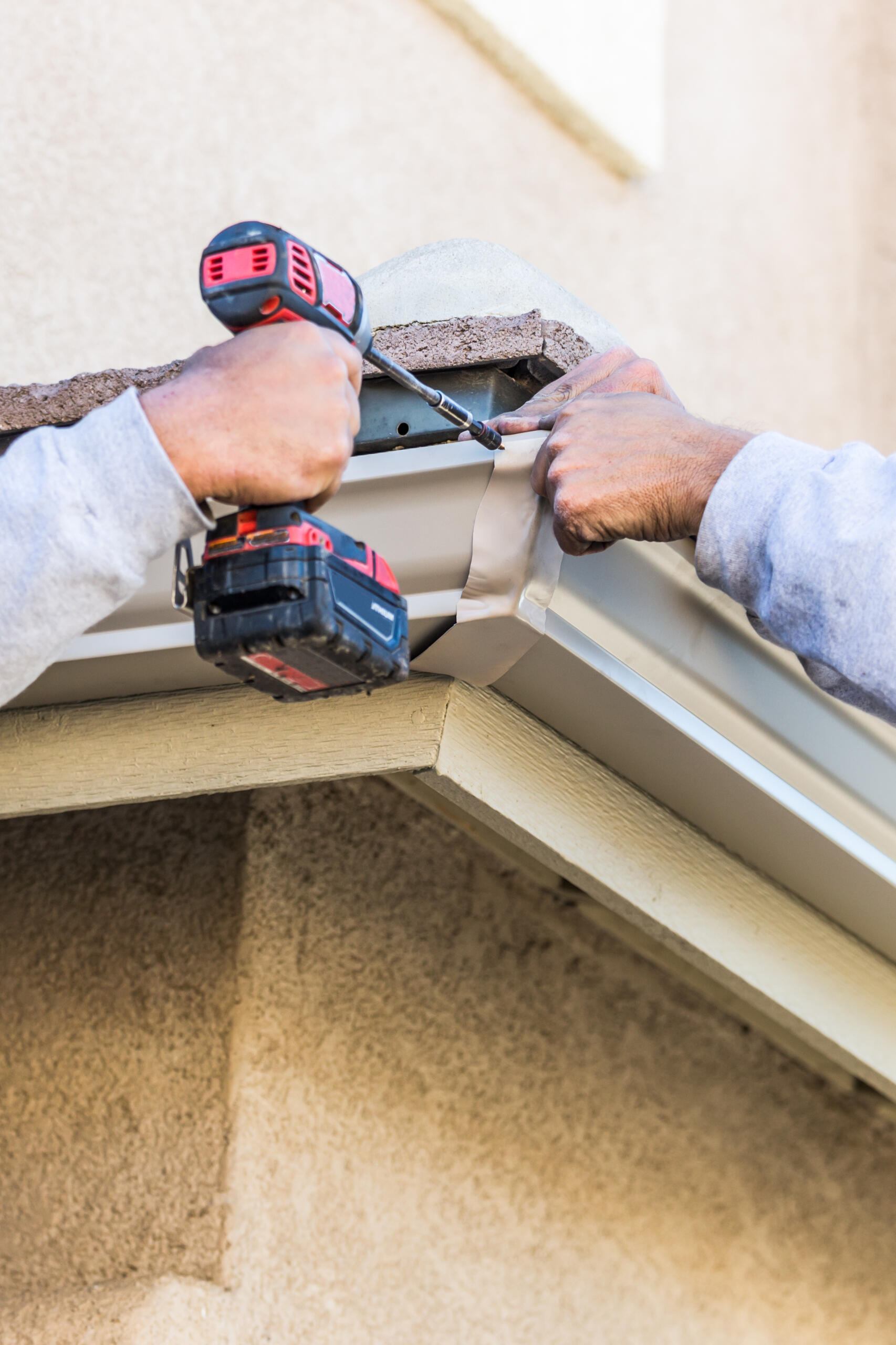 Professional installing seamless gutters on a residential home in Albuquerque. Corner.