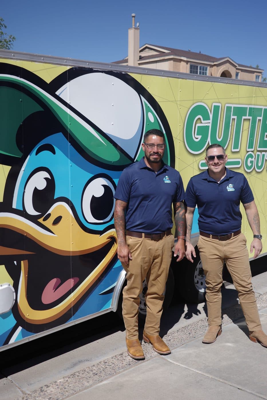 The Gutter Duck Gutters owners in front of their branded duck-wrapped trailer
