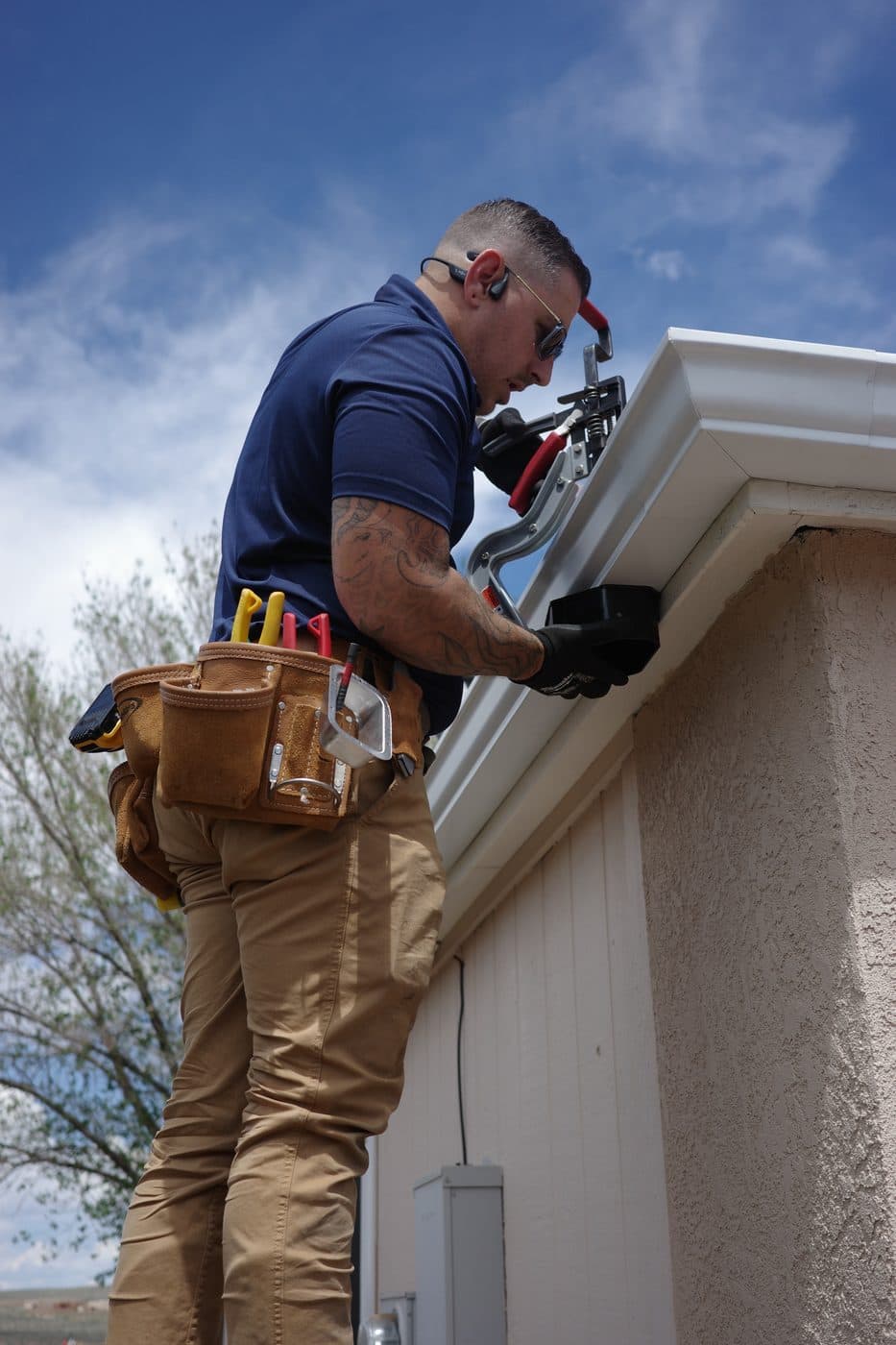 Technician on a ladder installing a new gutter on a stucco home