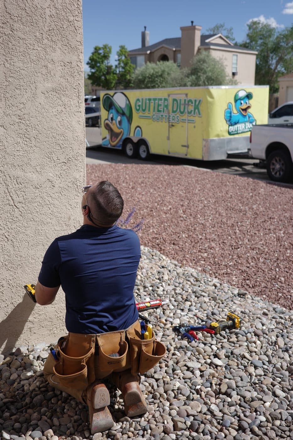 Technician on the job beside the branded Gutter Duck Gutters trailer