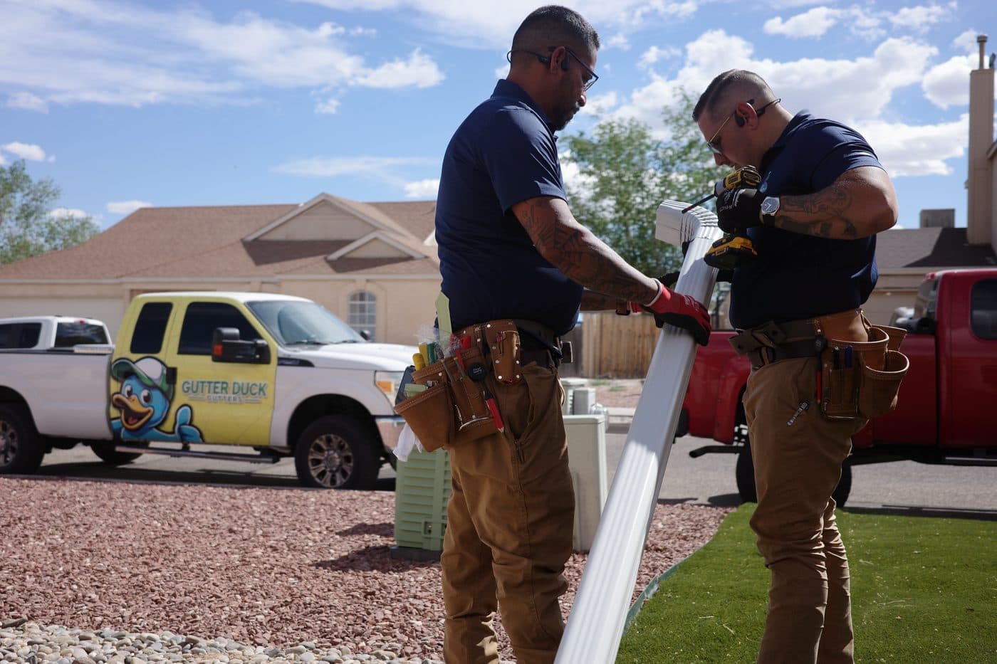 Crew carrying a new seamless gutter section across a front yard