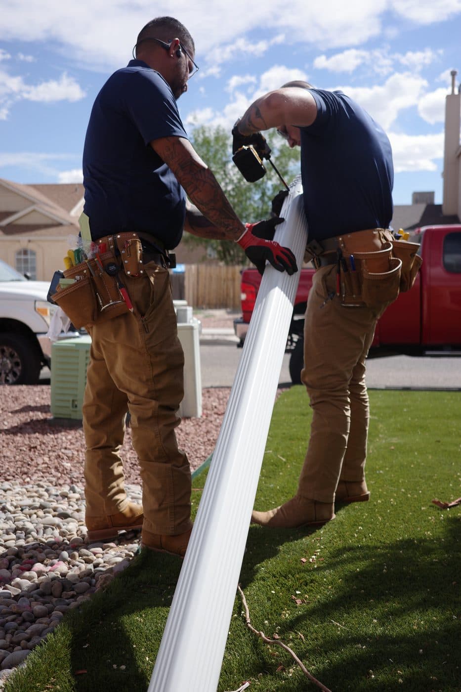 Gutter Duck Gutters crew carrying a new seamless gutter section at an Albuquerque home